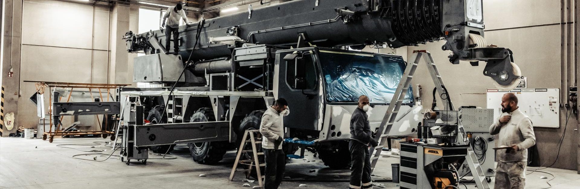 Eine Gruppe von Männern arbeitet in einem Lackierzentrum an einem großen Lastwagen.